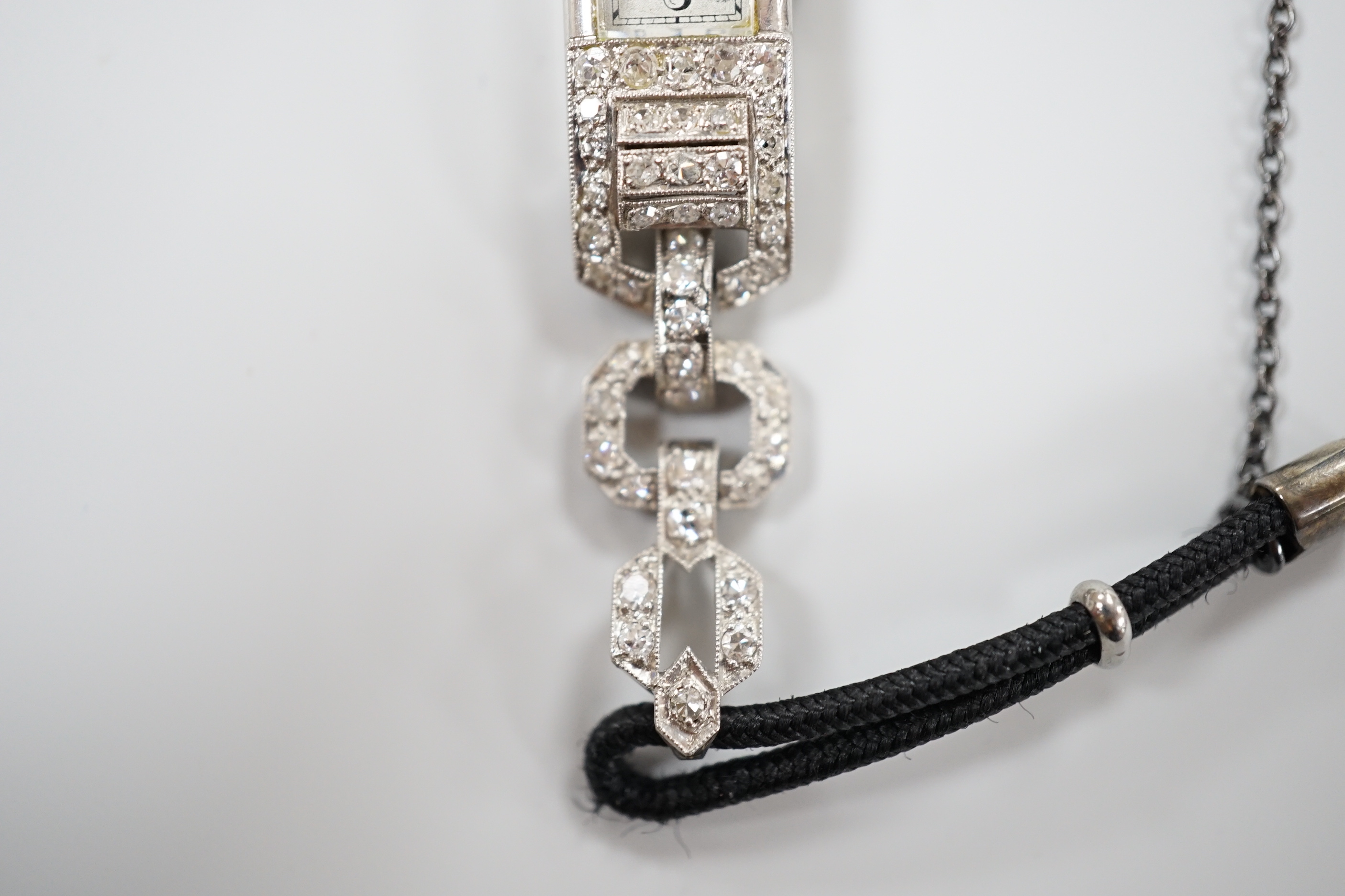 A lady's 1930's/2940's white metal (engraved All Platine) and diamond set manual wind cocktail watch, on a twin fabric strap.